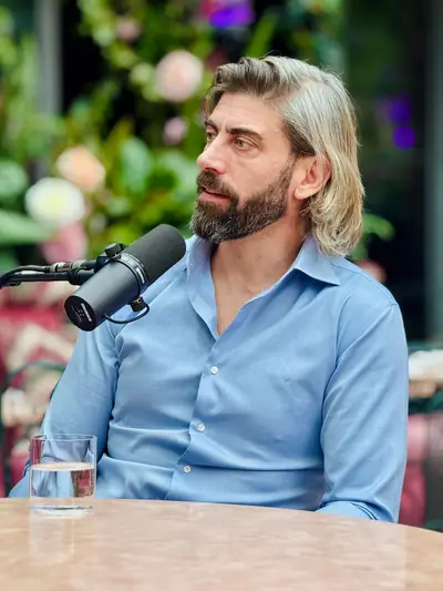 Guest in a blue shirt recording a podcast against a floral backdrop