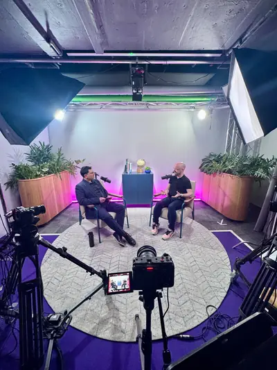 Wide view of a purple-lit professional studio during a video podcast recording