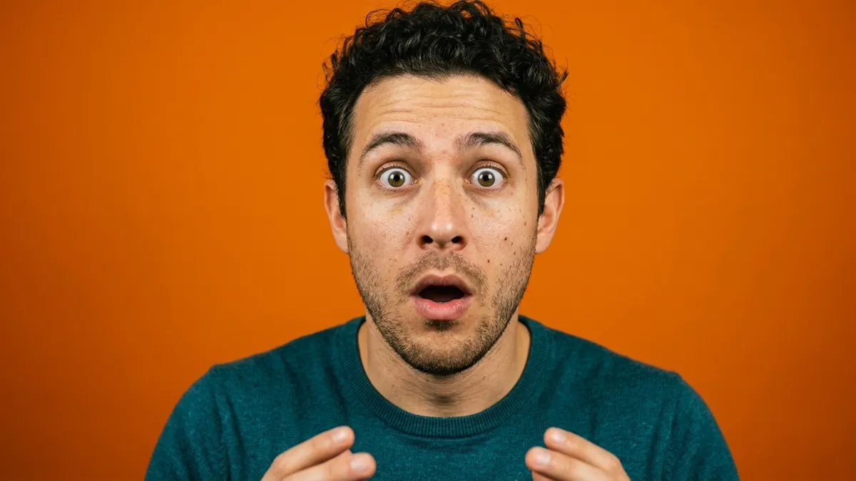 Wide-eyed man gasping against an orange backdrop, reacting to a free ebook on how to start a podcast